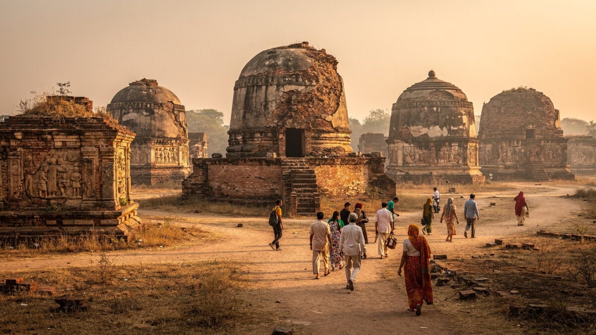 Ancient Buddhist stupa ruins at Sarnath, Uttar Pradesh, with pilgrims in afternoon light