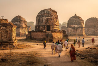 Ancient Buddhist stupa ruins at Sarnath, Uttar Pradesh, with pilgrims in afternoon light