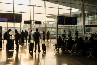 Bangkok airport departure hall with travelers and flight displays, morning light