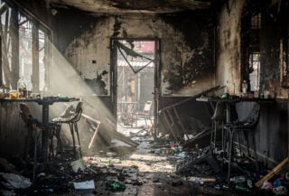 Charred interior of Bangkok bar with blocked emergency exit, smoke damage visible