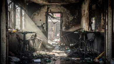 Charred interior of Bangkok bar with blocked emergency exit, smoke damage visible