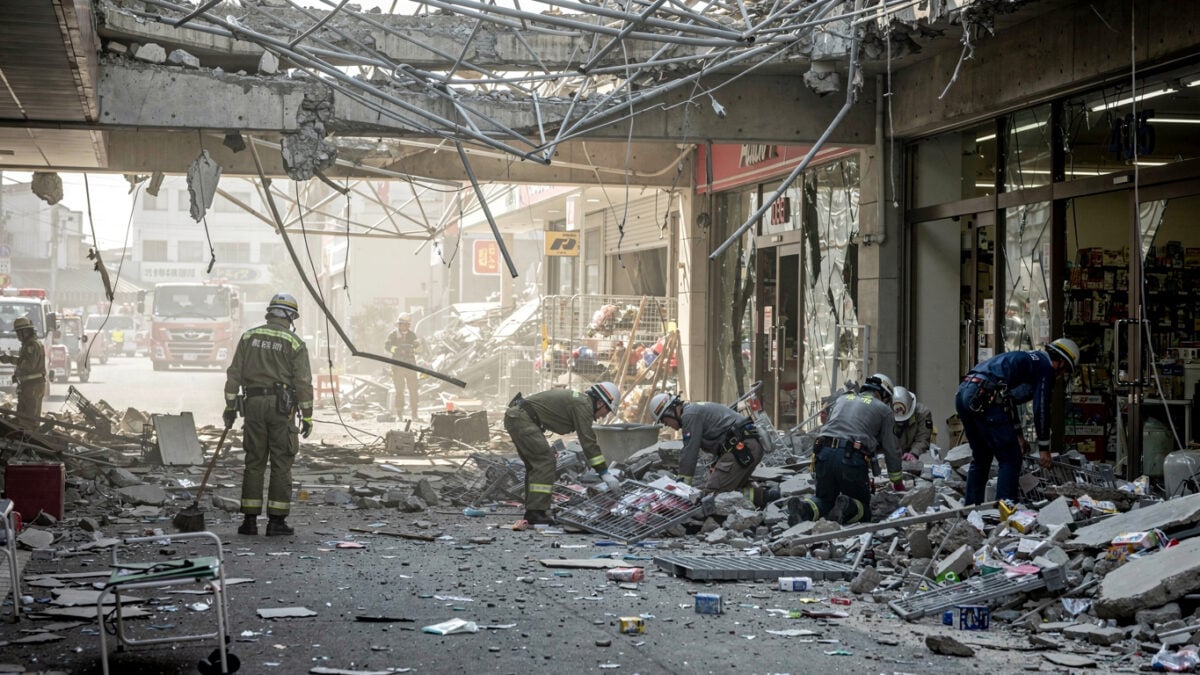 Collapsed Aeon Mall in Kumamoto, Japan, with rescue workers searching through rubble