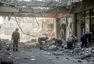 Collapsed Aeon Mall in Kumamoto, Japan, with rescue workers searching through rubble