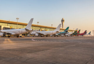 Commercial aircraft at Dubai International Airport terminal under morning light