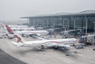 Commercial aircraft at Shanghai Pudong International Airport terminal, overcast daylight