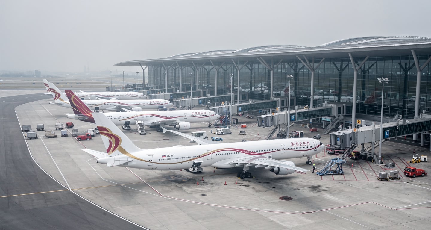 Commercial aircraft at Shanghai Pudong International Airport terminal, overcast daylight