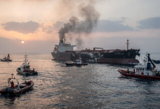 Damaged tanker in Strait of Hormuz with rescue vessels responding