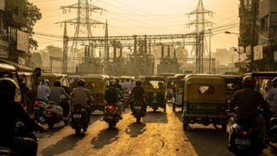 Delhi street traffic with three-wheelers and two-wheelers, power lines overhead
