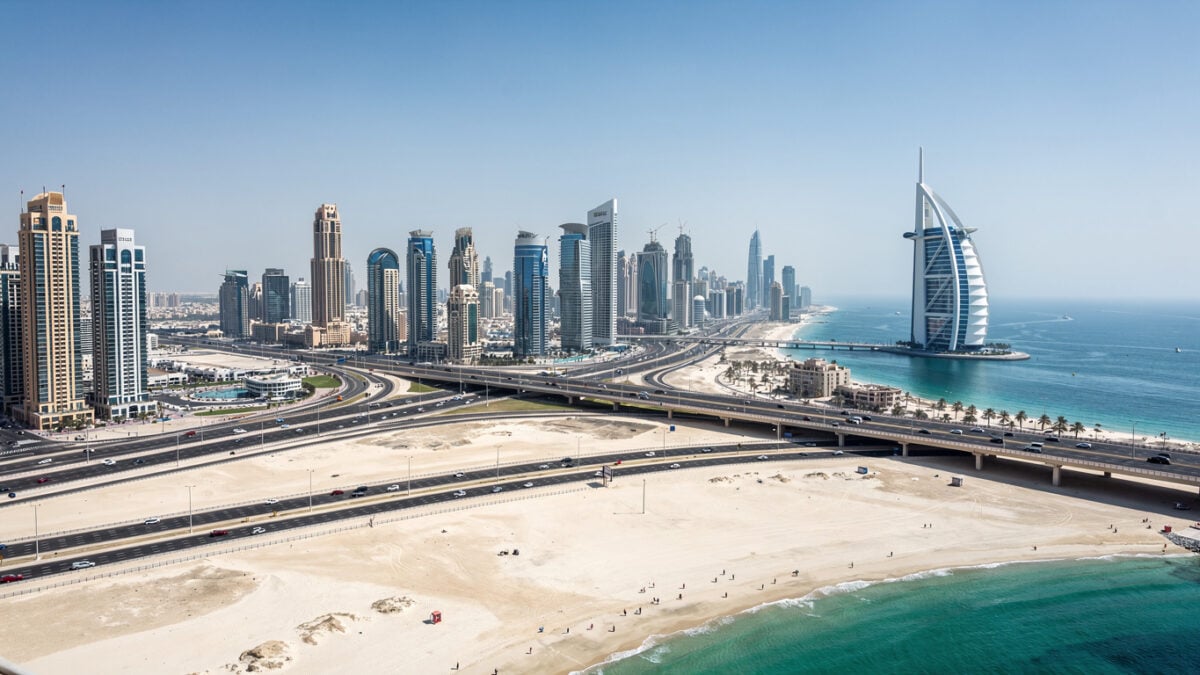 Dubai skyline with sparse tourist crowds, Burj Al Arab visible in distance