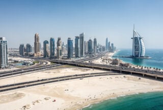 Dubai skyline with sparse tourist crowds, Burj Al Arab visible in distance