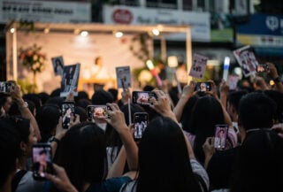 Fans at a Korean celebrity fan meeting event in Manila, holding phones and merchandise