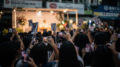 Fans at a Korean celebrity fan meeting event in Manila, holding phones and merchandise