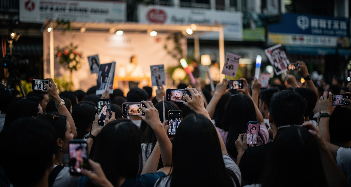 Fans at a Korean celebrity fan meeting event in Manila, holding phones and merchandise