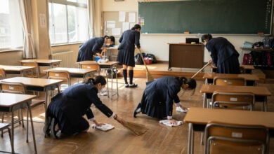 Japanese students cleaning classroom with brooms during school day