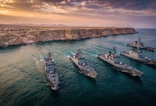 Naval vessels transiting the Strait of Hormuz near Iranian coast