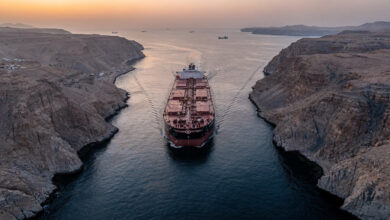 Oil tanker transiting Strait of Hormuz at dawn, narrow waterway between Iran and Oman