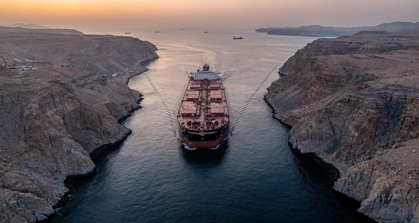 Oil tanker transiting Strait of Hormuz at dawn, narrow waterway between Iran and Oman