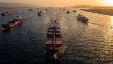 Oil tanker navigating Strait of Hormuz at dusk with container ships in narrow waterway