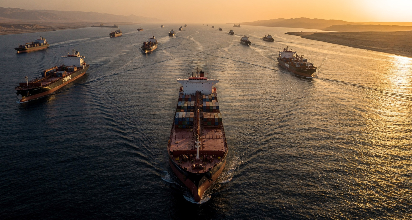 Oil tanker navigating Strait of Hormuz at dusk with container ships in narrow waterway
