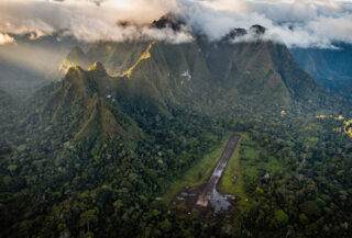 Papua highlands airstrip surrounded by dense jungle and mountains at dawn