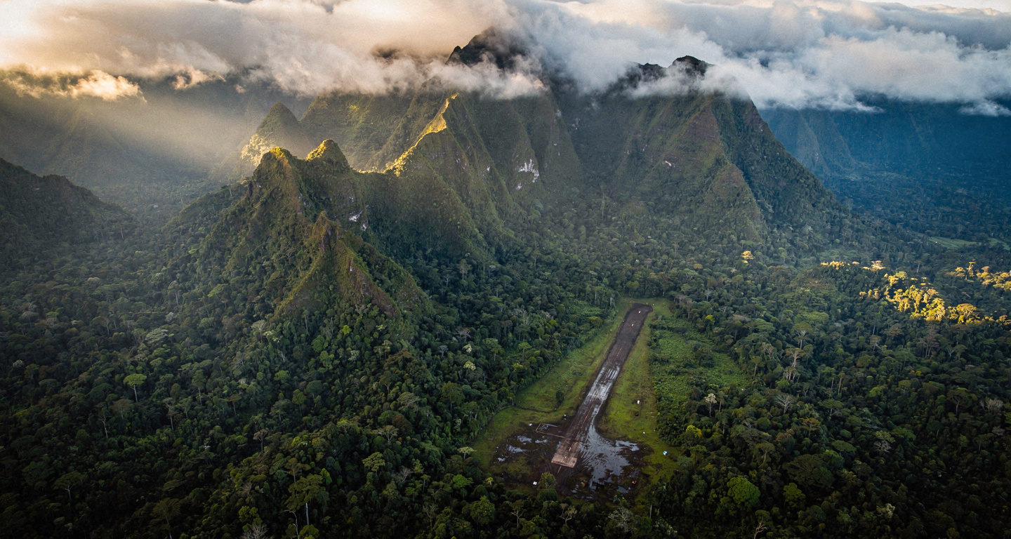 Papua highlands airstrip surrounded by dense jungle and mountains at dawn