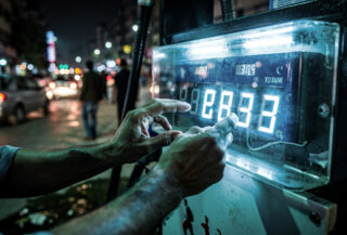 Petrol pump price display being adjusted, Islamabad street, night lighting