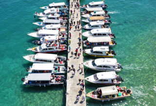 Phu Quoc island pier with multiple speedboats loading tourists, aerial view, turquoise water