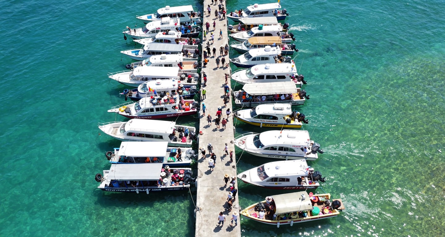 Phu Quoc island pier with multiple speedboats loading tourists, aerial view, turquoise water