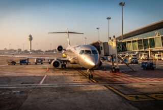 Regional jet aircraft on tarmac at Indian airport terminal, golden hour lighting