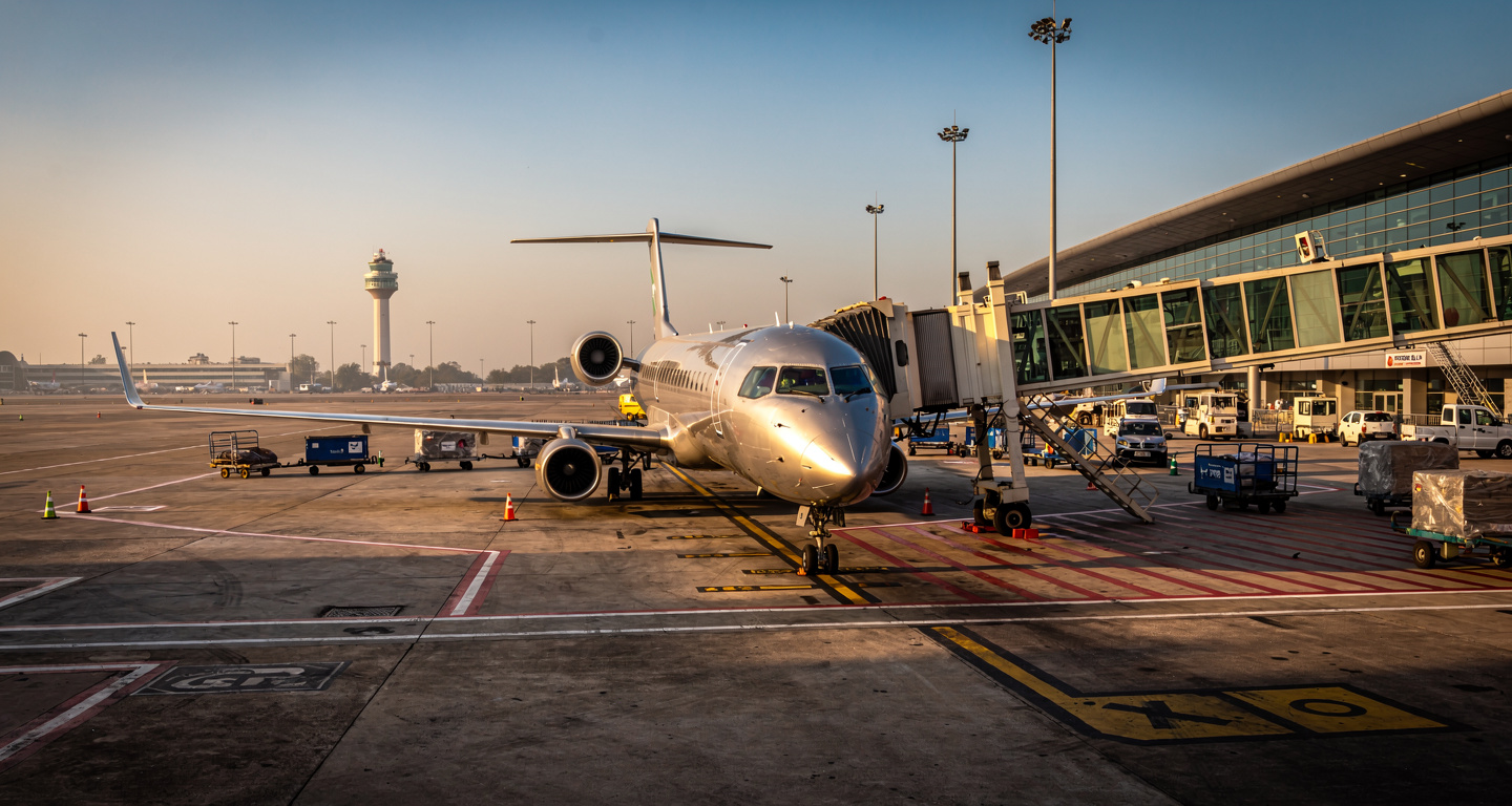 Regional jet aircraft on tarmac at Indian airport terminal, golden hour lighting