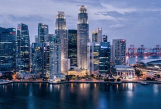 Singapore financial district skyline at dusk, Marina Bay with illuminated towers and harbor cranes
