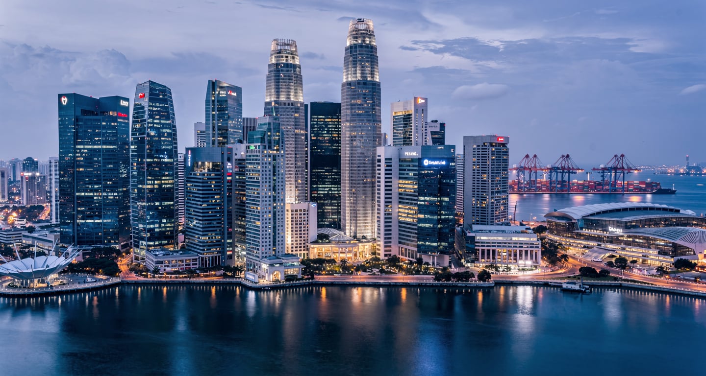 Singapore financial district skyline at dusk, Marina Bay with illuminated towers and harbor cranes