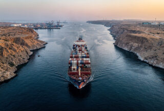 Tanker ship transiting narrow Strait of Hormuz waterway at dawn