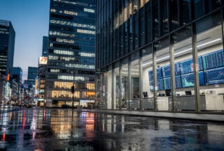 Tokyo financial district at dusk with currency trading screens visible through office windows