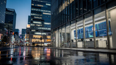Tokyo financial district at dusk with currency trading screens visible through office windows