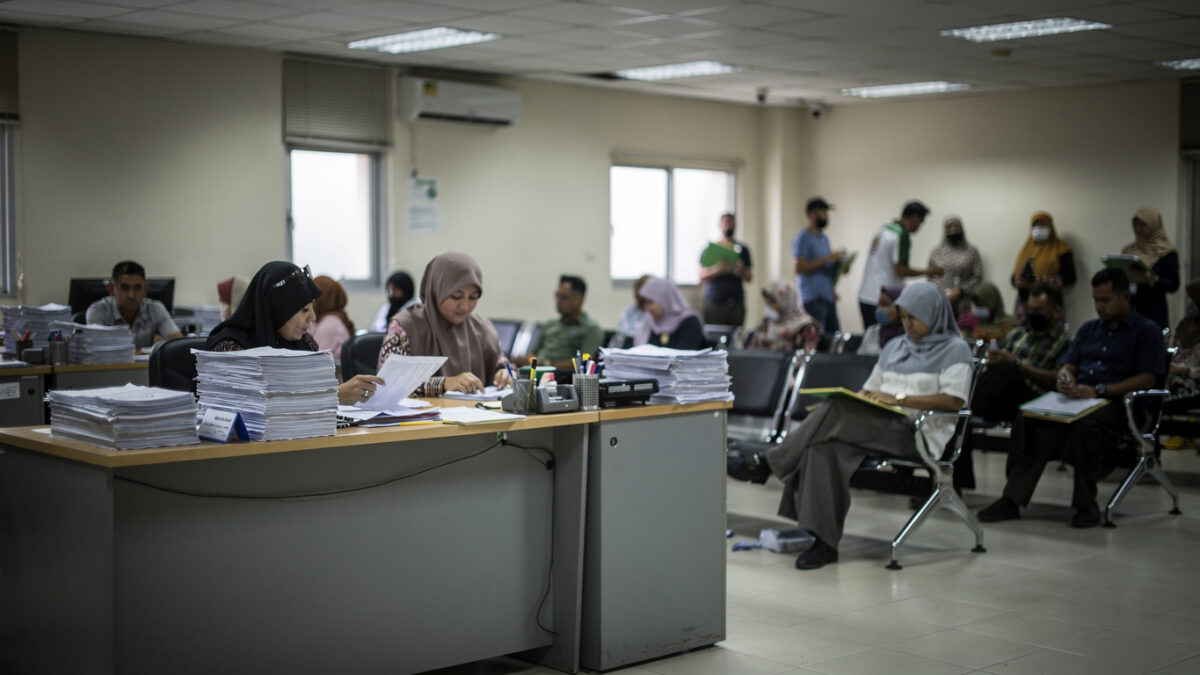 Administrative processing center interior, Malaysia, with staff screening documents at desks