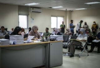 Administrative processing center interior, Malaysia, with staff screening documents at desks