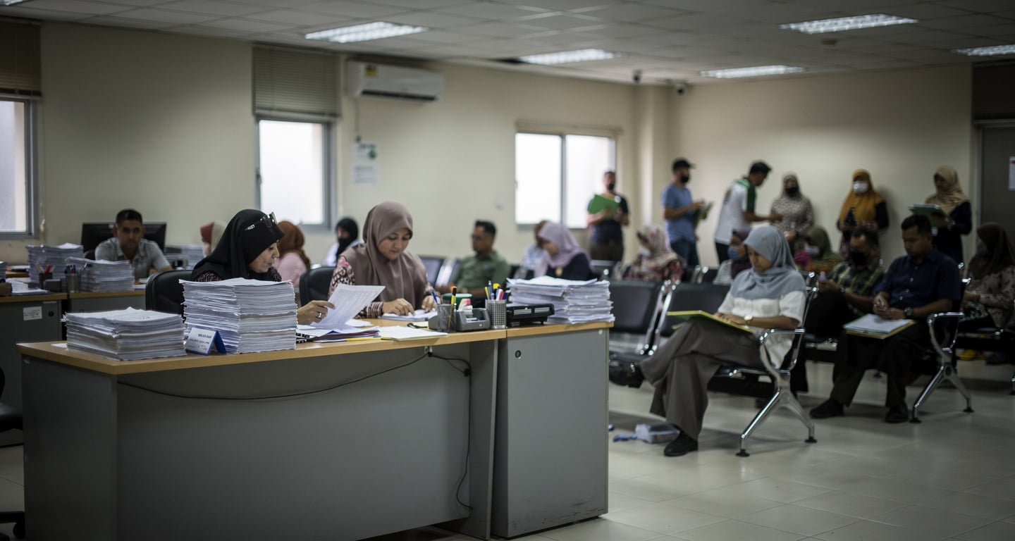 Administrative processing center interior, Malaysia, with staff screening documents at desks