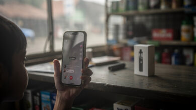 Child's hand with smartphone livestream interface, vaping shop counter background, Jakarta