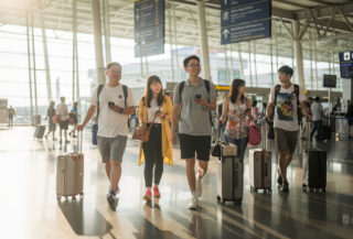 Chinese tourists with luggage at Bangkok airport arrivals, morning light