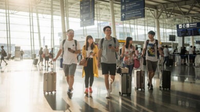 Chinese tourists with luggage at Bangkok airport arrivals, morning light