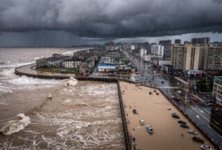 Coastal Zhejiang city under heavy typhoon rain and wind, dark dramatic sky