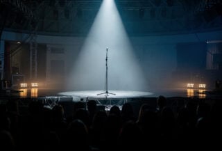 Concert stage at night with spotlight on microphone, Singapore venue, dramatic lighting
