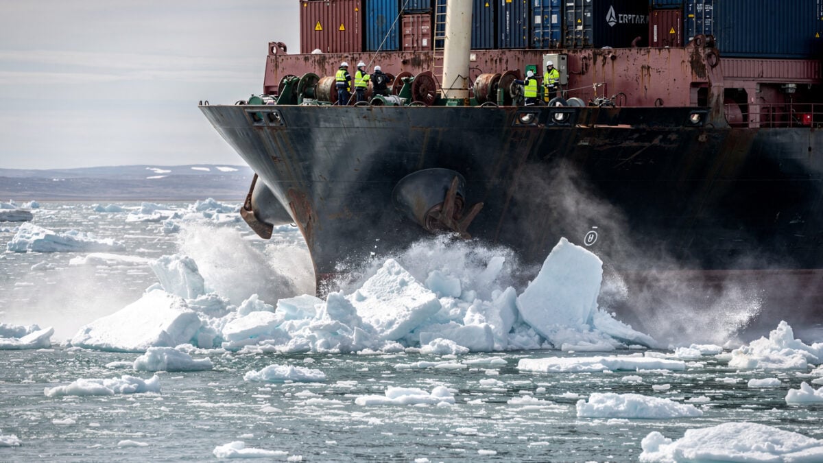 Container ship navigating through Arctic ice floes with crew monitoring deck operations, Bering Strait region