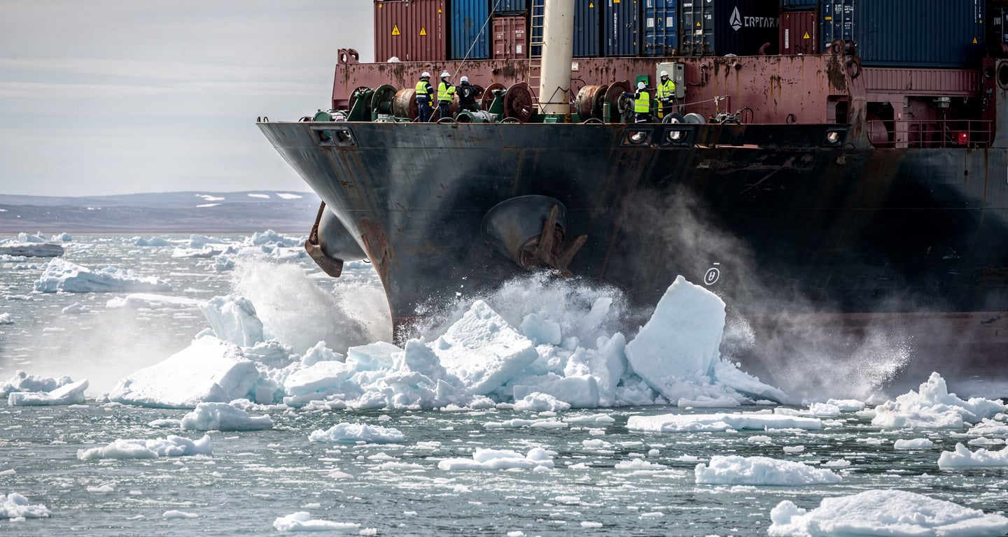 Container ship navigating through Arctic ice floes with crew monitoring deck operations, Bering Strait region
