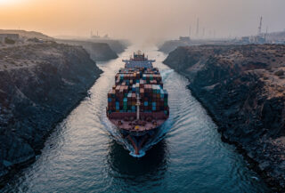Container ship in narrow strait passage between rocky coastlines, Strait of Hormuz