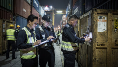 Customs officers inspecting shipping containers and export documents at Singapore port