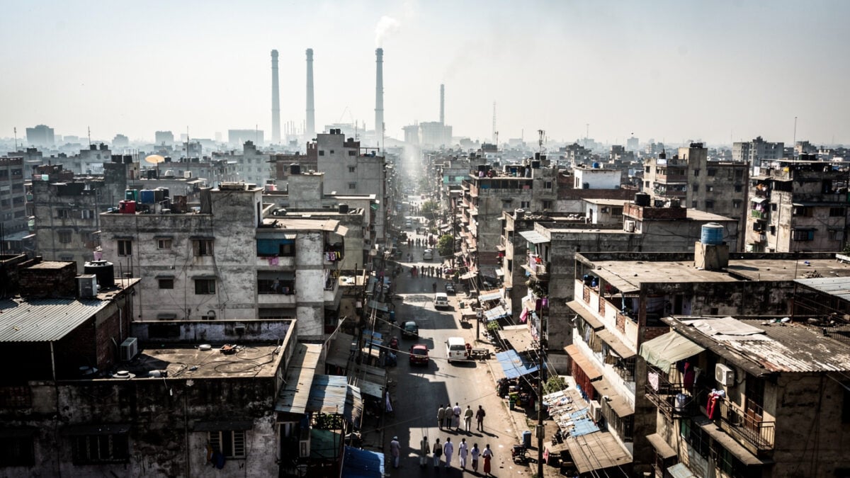 Dense South Asian city under intense midday heat with heat shimmer rising from concrete and asphalt streets