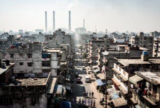 Dense South Asian city under intense midday heat with heat shimmer rising from concrete and asphalt streets