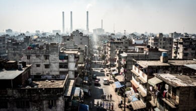 Dense South Asian city under intense midday heat with heat shimmer rising from concrete and asphalt streets